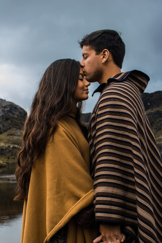 man kissing woman on forehead