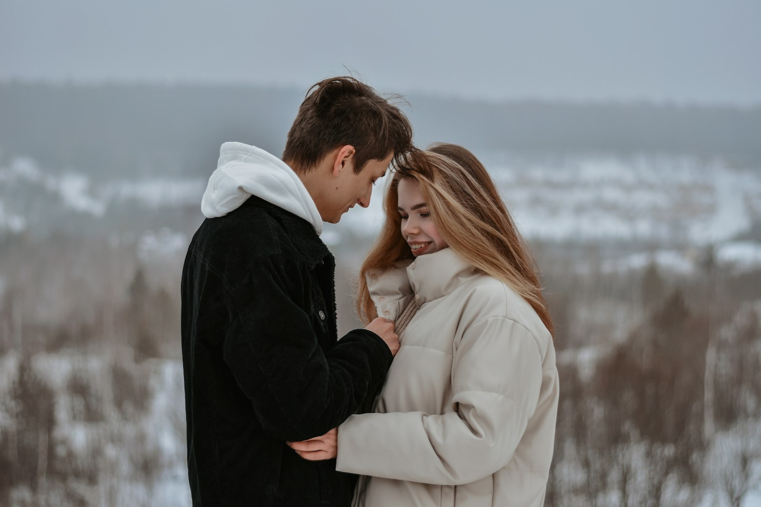 man in black suit kissing woman in white coat