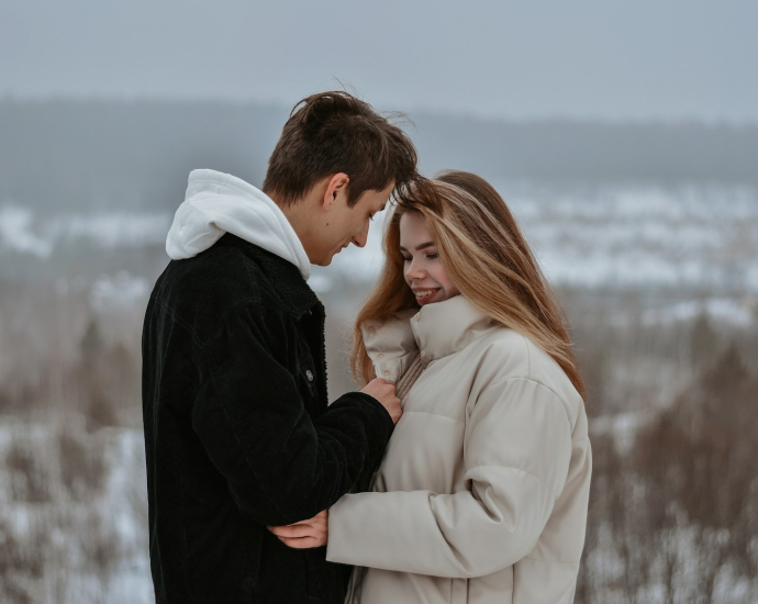 man in black suit kissing woman in white coat