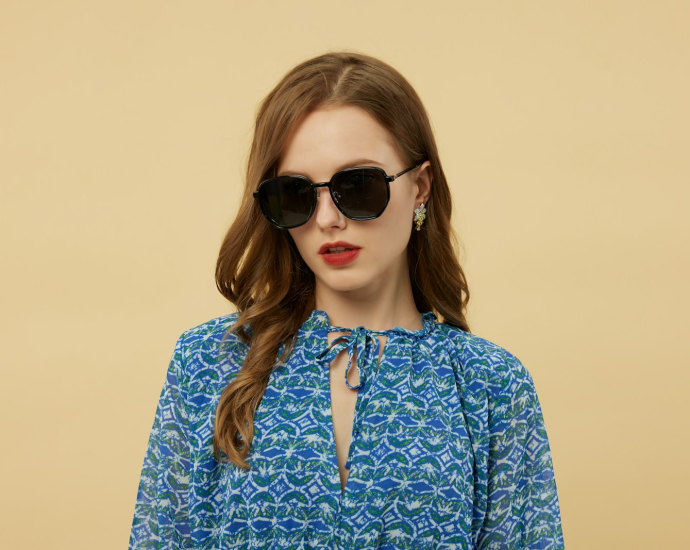 Woman wears sunglasses and a blue patterned dress.