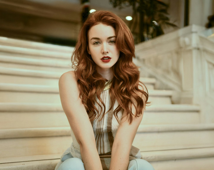 A woman with red hair sitting on a set of stairs